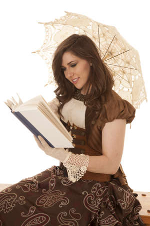 A woman sitting and reading her book with her umbrella with a big smile on her face.の写真素材