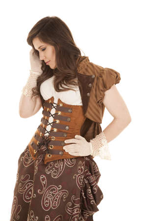 A woman in her vintage dress looking down with her gloved hand in her hairの写真素材