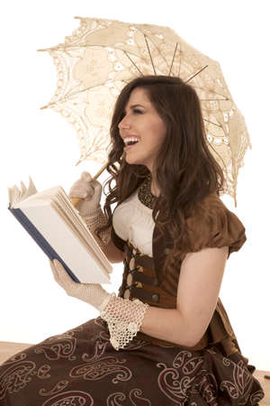 A woman sitting reading a book laughing at something in it.の写真素材