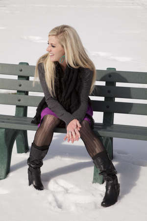 A woman with a  smile on her face sitting on a bench in the outdoors.の写真素材