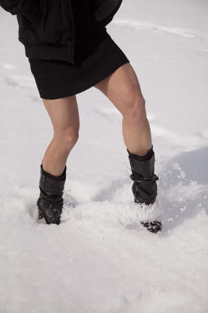 A woman's legs using her boots to kick up snowの写真素材