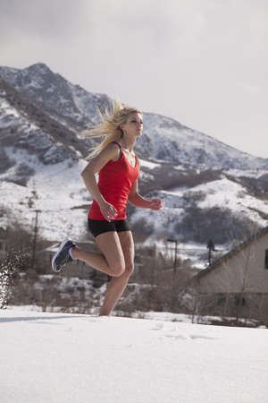 A woman running in the snow and cold to be fit and healthy.の写真素材