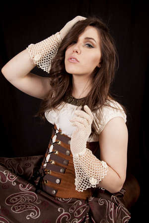A woman in her vintage dress looking down with her gloved hand in her hairの写真素材
