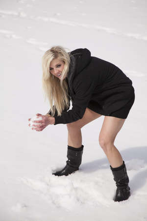 A woman with a smile on her face with a snowball in her hand.の写真素材