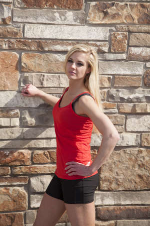 a woman in her fitness clothes standing up by a brick wallの写真素材