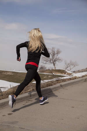 A woman running up a road in the winter time.の写真素材