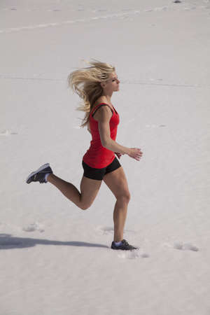 A woman running in her shorts and tank in the snow.の写真素材