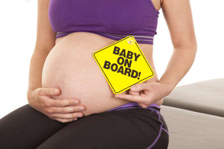 A close up of a woman's belly who is expecting a baby holding  asign by her bellyの写真素材