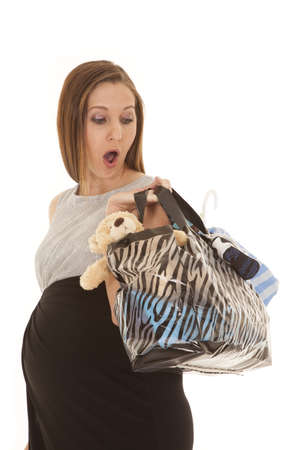 A woman expecting a baby just finished shopping with a shocked expression on her face looking into her bagの写真素材