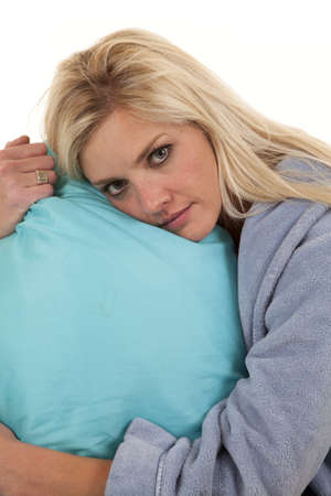 a woman holding on to her pillow while she is wearing her robeの写真素材