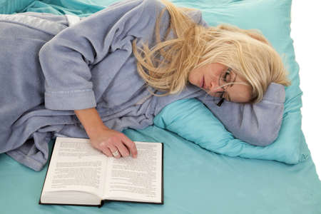 A woman who is asleep while she is wearing her glasses and her book openの写真素材