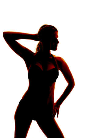 A woman is standing in a bathing suit.  She is a silhouette.の写真素材