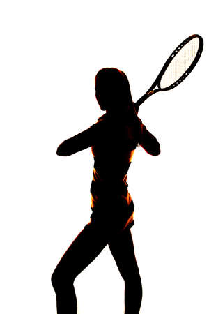 A silhouette of a woman standing holding on to her tennis racquet.の写真素材