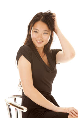 A woman with a smile on her lips with her hand in her hair and a smile on her face.の写真素材