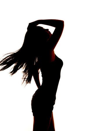 A silhouette of a woman leaning back with the wind blowing her hair.の写真素材