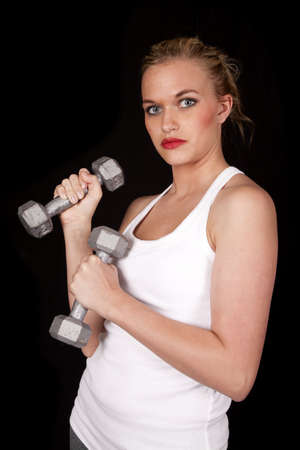 a woman working out with her weights with a serious expression.