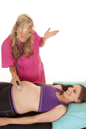 a nurse with an unsure expression on her face listening to a pregnant woman's belly