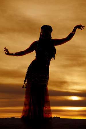 a silhouette of a woman belly dancing in the beautiful sunsetの写真素材