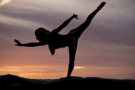 A silhouette of a woman doing a dance pose in the outdoors