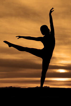 A silhouette of a woman doing a dance pose in the outdoorsの写真素材