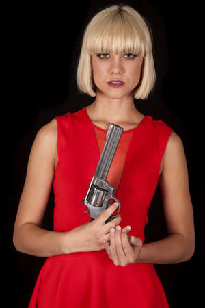 A woman in a red dress holding a revolver.の写真素材
