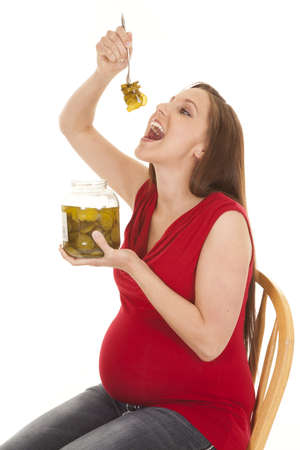 A pregnant woman getting ready to eat a big forkful of pickles.の写真素材