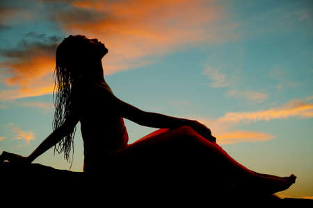 A silhouette of a woman leaning back with her braids falling back.の写真素材