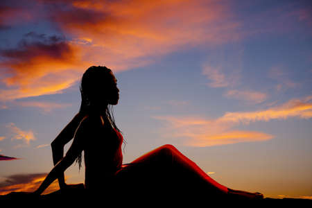 A silhouette of a woman sitting up with her braids falling back.の写真素材