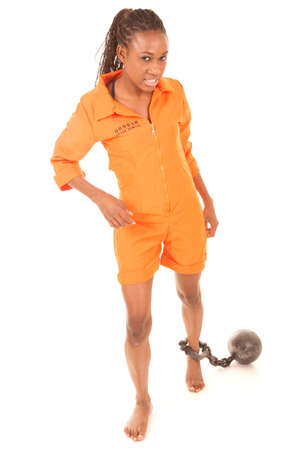 A woman trying to walk in her prison outfit with a ball and chain..