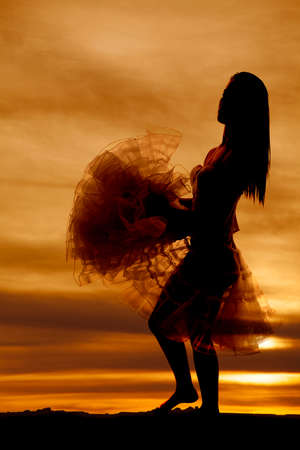 A silhouette of a woman holding her skirt.の写真素材