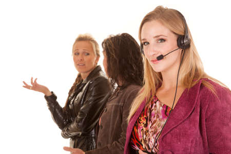 A business woman with her headset looking while two other business women are talking in the background.の写真素材