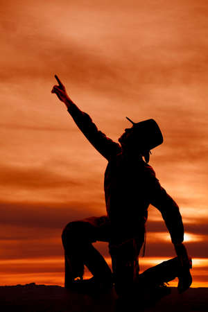 a silhouette of a cowboy reaching his arm up to the sky.の写真素材