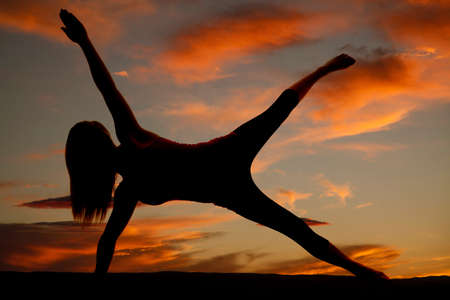 A silhouette of a woman on one hand and on one foot posing.