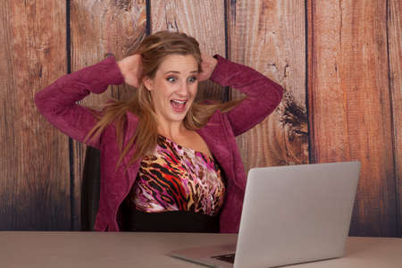 A woman with a shocked expression looking at her laptopの写真素材