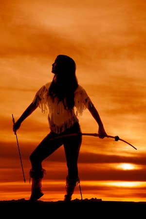 A silhouette of a Native American woman holding her bow and arrow by her side.の写真素材