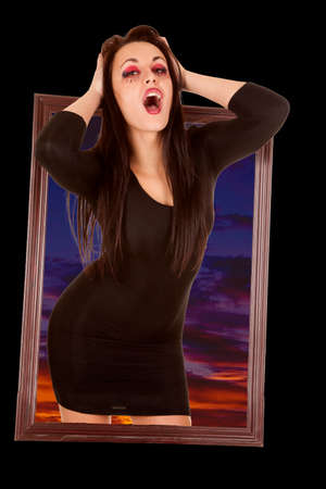 A woman vampire coming through picture frame with a night sky behind them.の写真素材