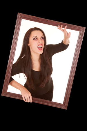 A female vampire coming through a window showing off her fangs.の写真素材