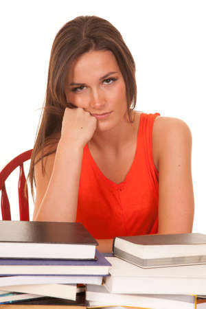 A woman is sitting at a desk with books with her fist by her face.の写真素材