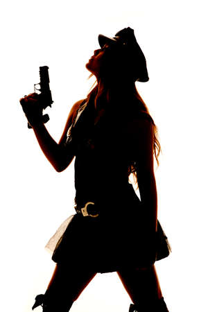 A silhouette of a female cop holding a gun and looking up.の写真素材