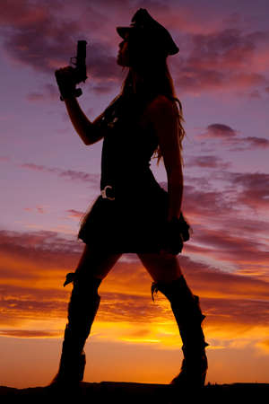A silhouette of a female cop holding her gun up.の写真素材