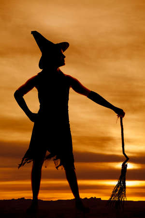 A silhouette of a woman holding her broom and wearing a witch hat.の写真素材