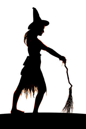 A silhouette of a woman holding her broom and facing sideways.の写真素材