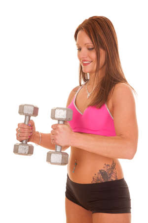 A woman in a pink sports bra is holding weights.の写真素材