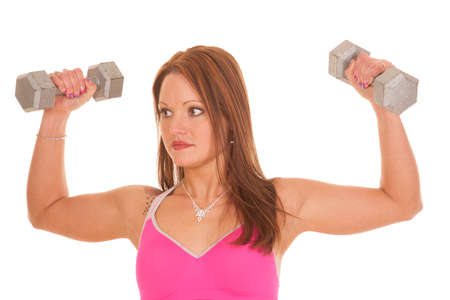 A woman is holding up weights and looking to the side.の写真素材