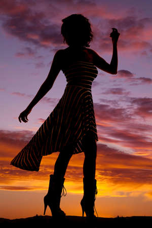 A silhouette of a woman with her dress blown.の写真素材
