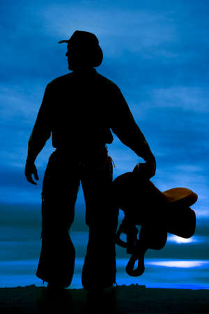a silhouette of a cowboy holding on to his saddle.の写真素材