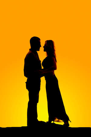 A silhouette of a man and woman standing close together.の写真素材