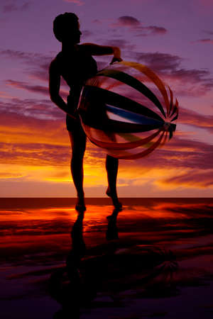 A silhouette of a woman holding on to her beach ball.の写真素材