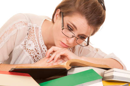 a woman laying on a stack of books looking down at her book.の写真素材