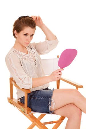 a woman fixing her hair in the mirror she is holding.の写真素材